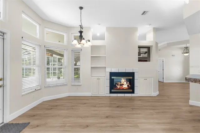 an empty room with wooden floor ceiling fan and windows