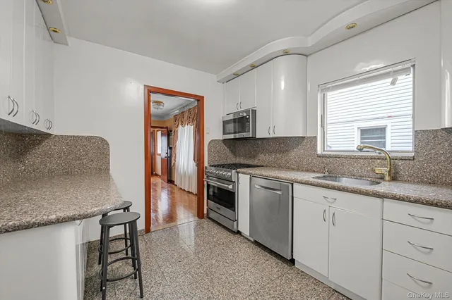 a kitchen with granite countertop stainless steel appliances a sink stove and cabinets