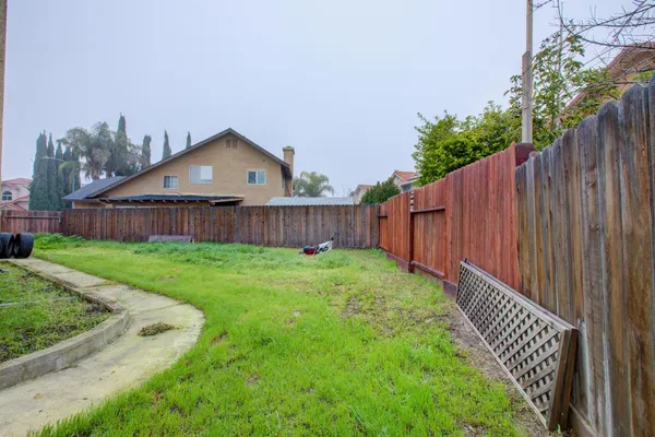 a view of a house with backyard and wooden fence