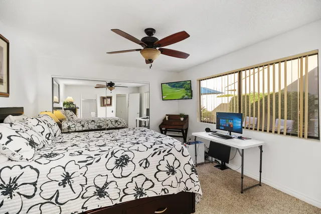 a bedroom with a bed a desk and chair with window