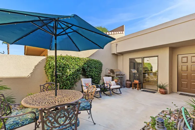 a patio with a table and chairs under an umbrella