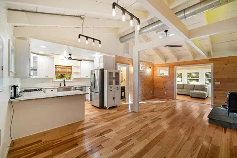 a open kitchen with stainless steel appliances granite countertop a refrigerator a sink dishwasher and a stove with wooden floor