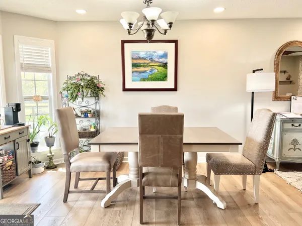 a dining room with wooden floor a chandelier a glass table and chairs