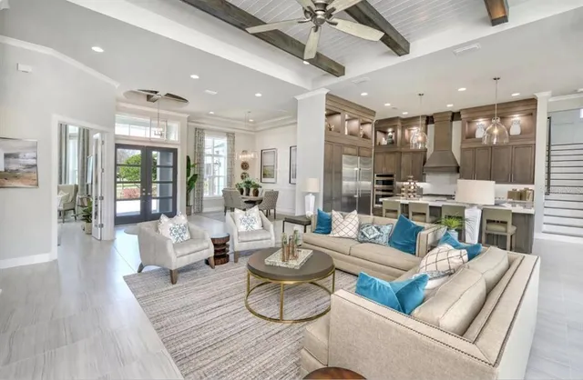 a living room with furniture kitchen view and a large window
