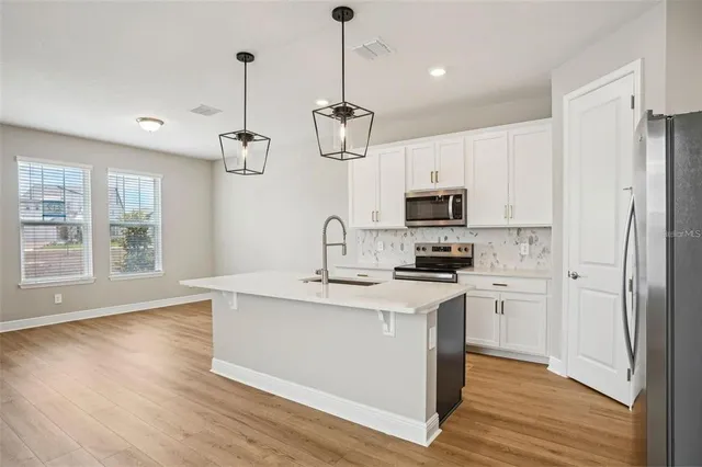 a kitchen with stainless steel appliances granite countertop a sink a stove a refrigerator cabinets and wooden floor