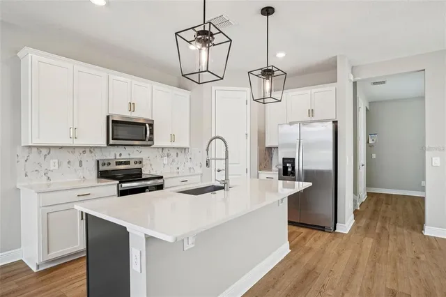 a kitchen with stainless steel appliances granite countertop a sink a stove a refrigerator cabinets and wooden floor