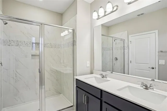 a bathroom with a double vanity sink mirror and shower