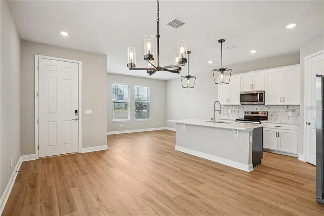 a kitchen with stainless steel appliances kitchen island wooden floors stove and white cabinets