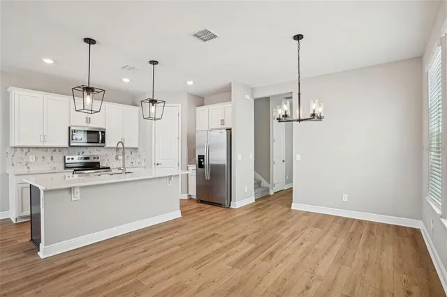 a kitchen with stainless steel appliances kitchen island a refrigerator and a wooden floor