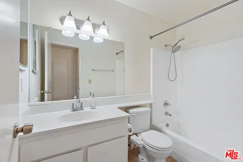 a bathroom with a sink a toilet a mirror a vanity and shower
