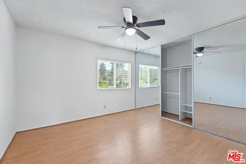 an empty room with windows and fan