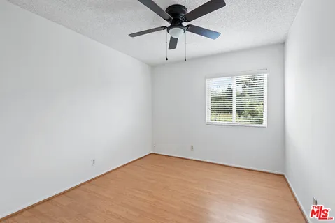 an empty room with a window and a fan
