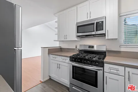 a kitchen with stainless steel appliances granite countertop white cabinets a stove top oven a sink and dishwasher