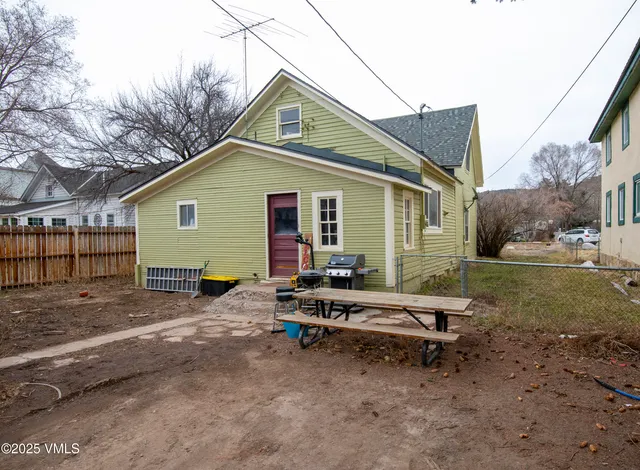 a backyard of a house with wooden fence and large trees