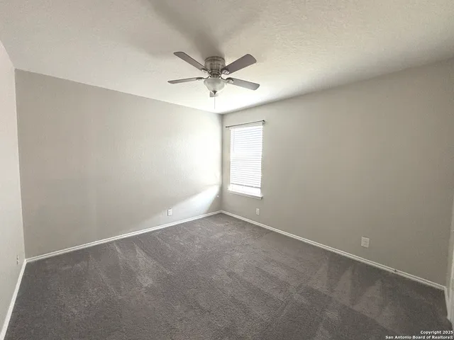 an empty room with a window and a fan