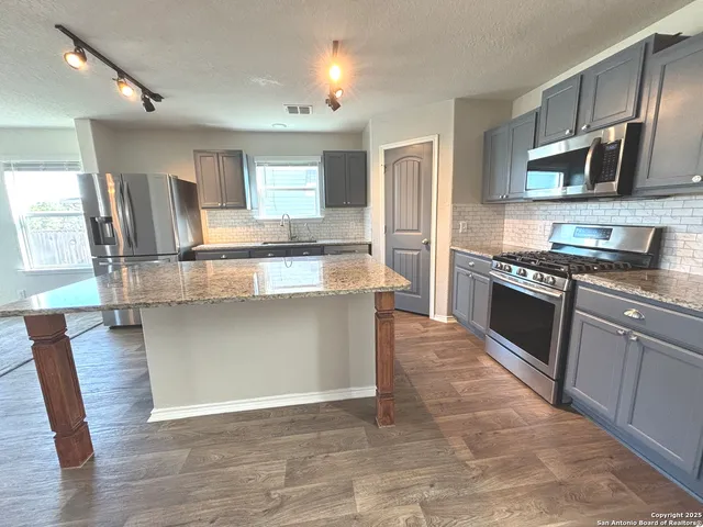 a large kitchen with stainless steel appliances granite countertop a stove a sink dishwasher and a refrigerator