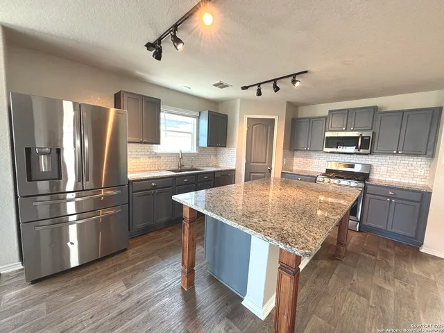 a kitchen with stainless steel appliances granite countertop a sink stove and refrigerator