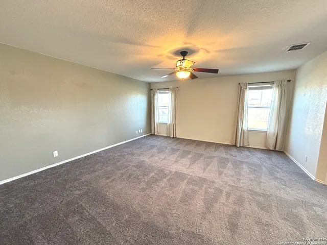 an empty room with windows and chandelier fan