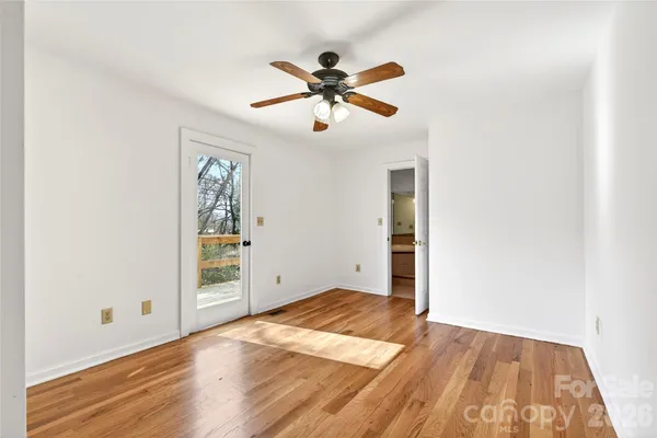 an empty room with wooden floor fan and windows