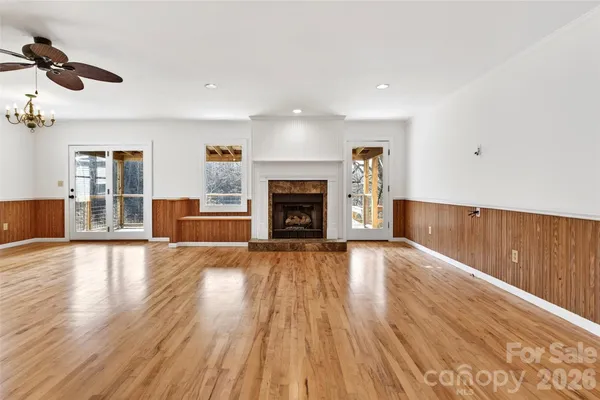 an empty room with wooden floor fireplace and windows