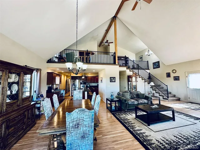 a kitchen with stainless steel appliances granite countertop a refrigerator a sink dishwasher a dining table and chairs with wooden floor