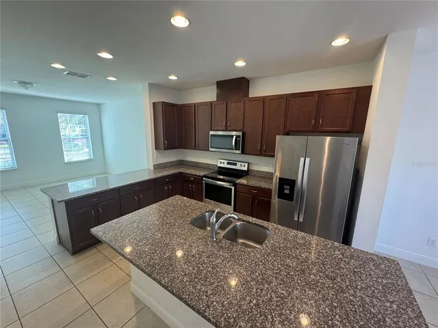 a kitchen with granite countertop a sink cabinets and refrigerator