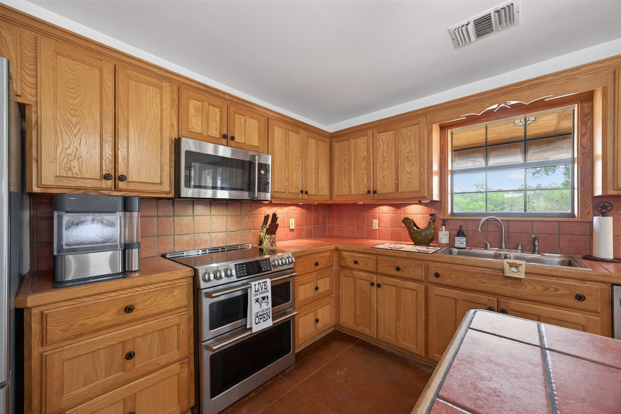 1077 Burdette Wells Road Lockhart, TX 78644 - Photo 15 of 38 a kitchen with stainless steel appliances wooden cabinets and a stove top oven