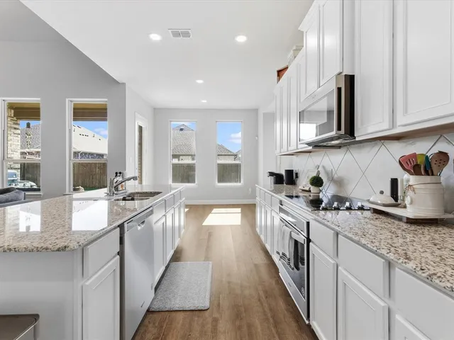 a large kitchen with stainless steel appliances granite countertop a lot of counter space and wooden floor