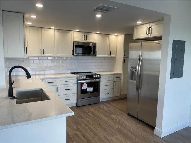 a kitchen with stainless steel appliances a refrigerator a sink a stove and cabinets