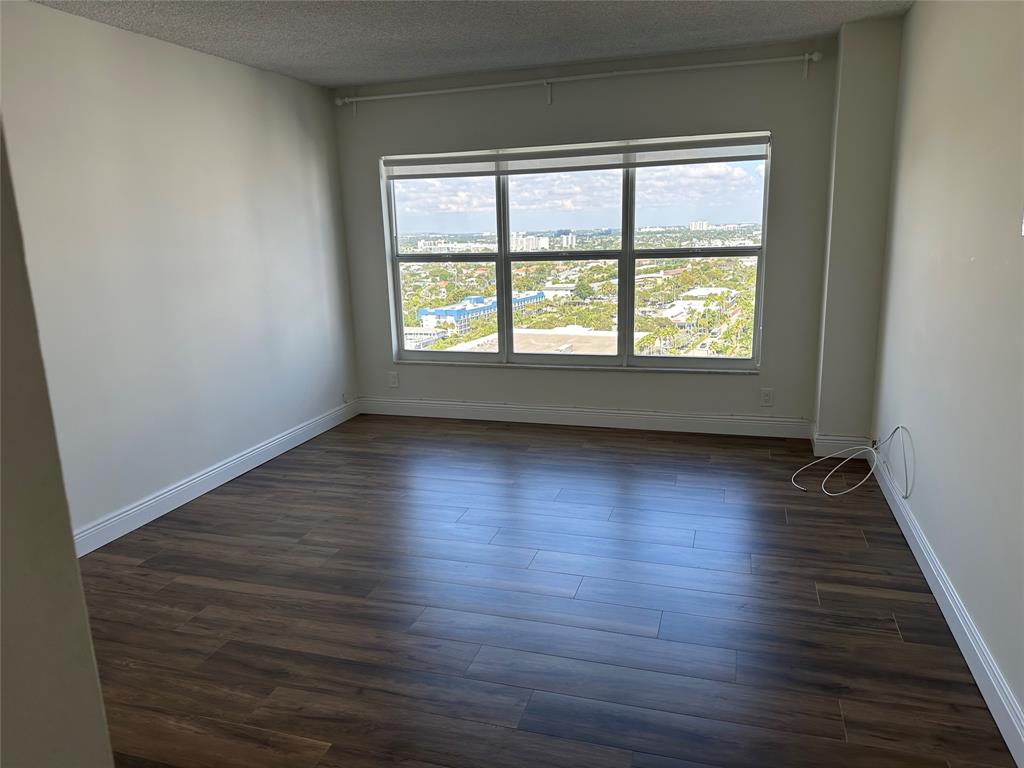 3550 Galt Ocean Drive, Unit 1907 Fort Lauderdale, FL 33308 - Photo 9 of 28 an empty room with wooden floor and windows with curtains