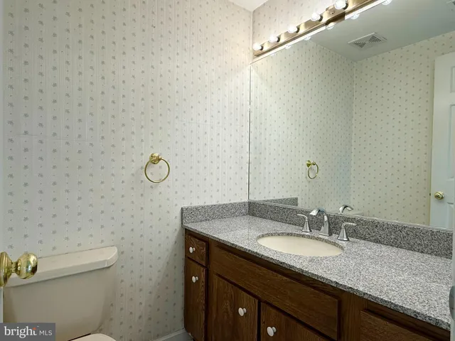 a bathroom with a granite countertop sink a toilet and a mirror