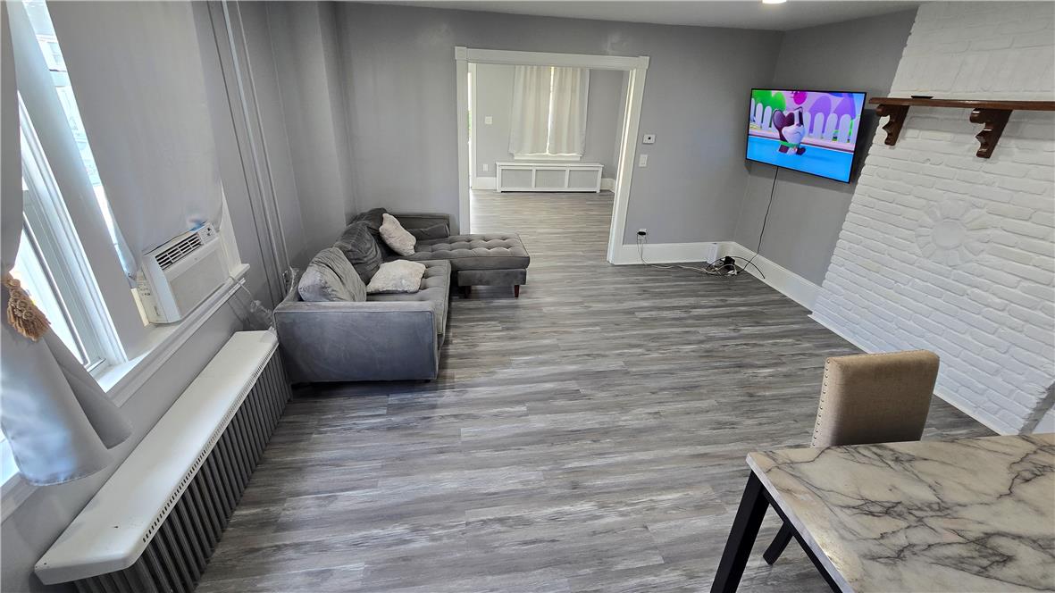 883 North Locust Street Hazleton, PA 18201 - Photo 69 of 83 Laminate wood flooring sweeps across this open concept living space, anchored by a unique whitewashed brick fireplace feature.