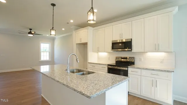 a kitchen with kitchen island granite countertop a sink a stove and oven