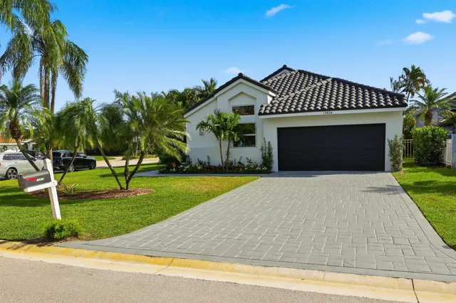 a view of a house with a big yard and palm trees
