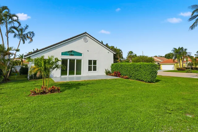 a view of a house with a yard and palm trees