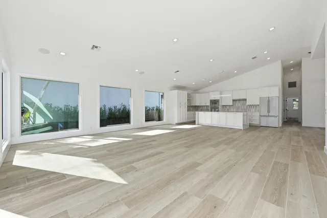 a large white kitchen with kitchen island a sink a stove and white cabinets