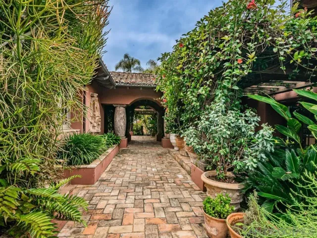 a front view of a house with large trees and outdoor seating