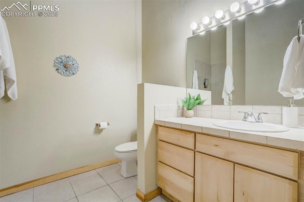 115 North Tejon Street, Unit B Colorado Springs, CO 80903 - Photo 28 of 43 a bathroom with a granite countertop sink a toilet and a mirror