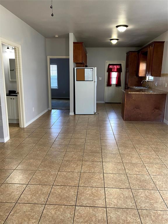 906 Parkplace Ridge Princeton, TX 75407 - Photo 28 of 31 Kitchen and living area featuring neutral tile flooring, warm wood cabinetry, a granite-finish countertop, and recessed ceiling lighting