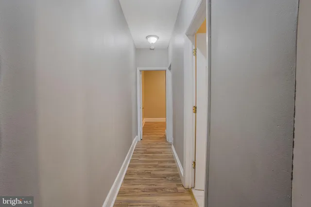 a view of a hallway with wooden floor and a bathroom