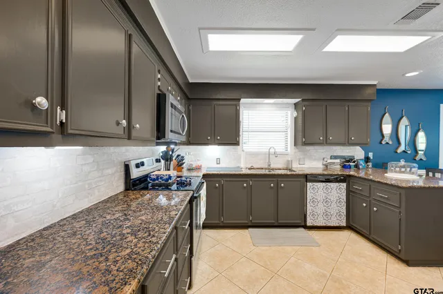 a kitchen with stainless steel appliances granite countertop a sink stove and cabinets