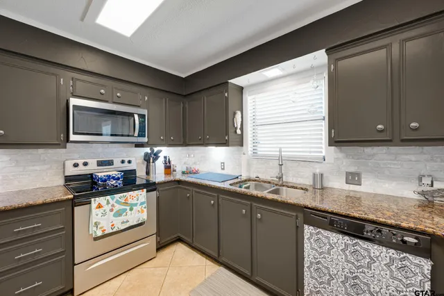 a kitchen with stainless steel appliances granite countertop a sink stove and microwave