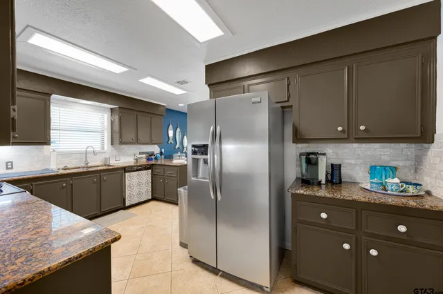 a kitchen with stainless steel appliances granite countertop a refrigerator a sink and a stove