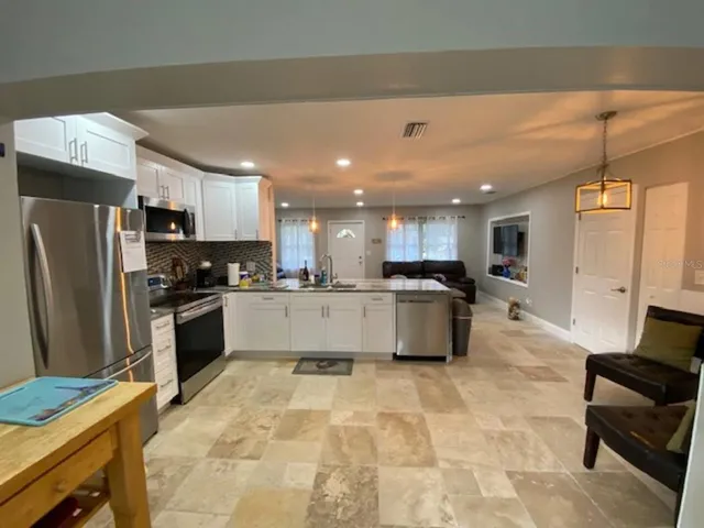 a large kitchen with stainless steel appliances kitchen island granite countertop a refrigerator and a stove top oven