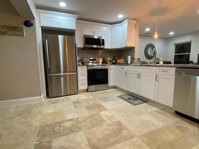 a kitchen with granite countertop a refrigerator and a stove top oven