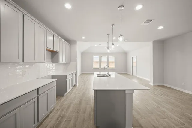 a kitchen with kitchen island granite countertop a sink cabinets and wooden floor