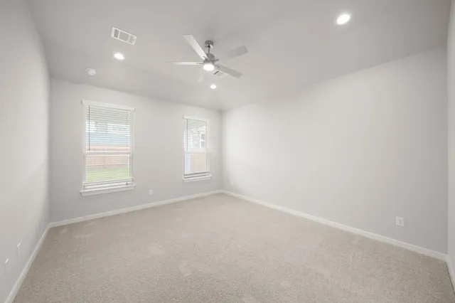 an empty room with windows and fan