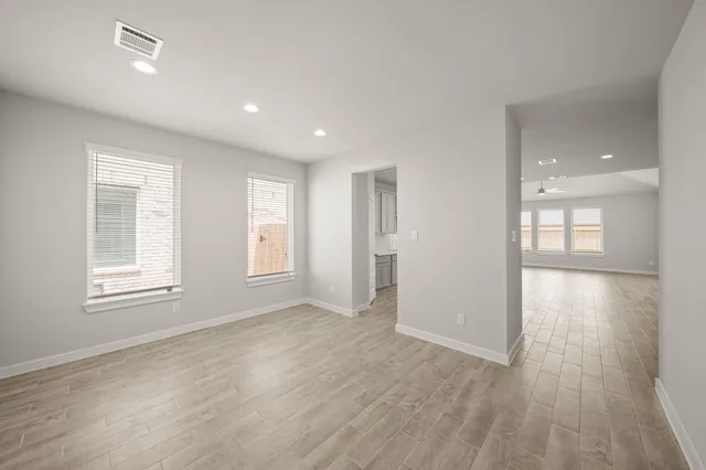 an empty room with wooden floor and windows