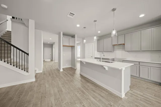 a large white kitchen with a large counter top a sink stainless steel appliances and cabinets