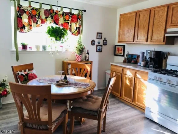 a view of a dining room with furniture a kitchen and wooden floor